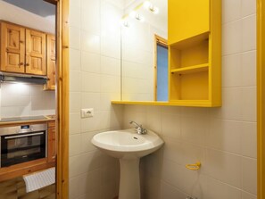 A bathroom with a white sink, a yellow medicine cabinet, and wooden cabinets. - Cardinello Rosa by Interhome (Madesimo)