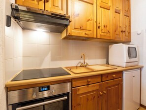 Eine kleine Küche mit Holdekor, einem Backofen, einer Mikrowelle und einem Spülbecken mit Armatur.