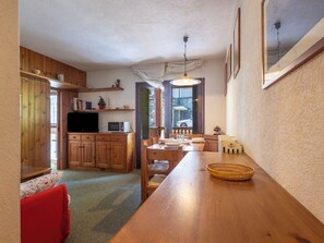 Eine gemütliche Küche mit Holzschränken, einem Esstisch und einem Fernseher.
