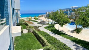 A modern hotel with a pool, a well-maintained lawn, and a view of the ocean. - Fouka North Coast SA-5A-102 (Marsa Matrouh)