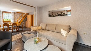A living room with a sofa, coffee table, and a dining area with chairs and a table.