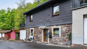 A two-story building with a stone facade, a wooden door, and a small window.