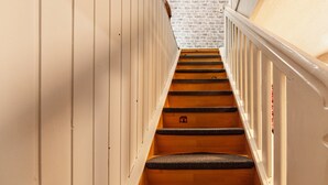 A staircase with wooden steps and white railings, leading to a brick wall.
