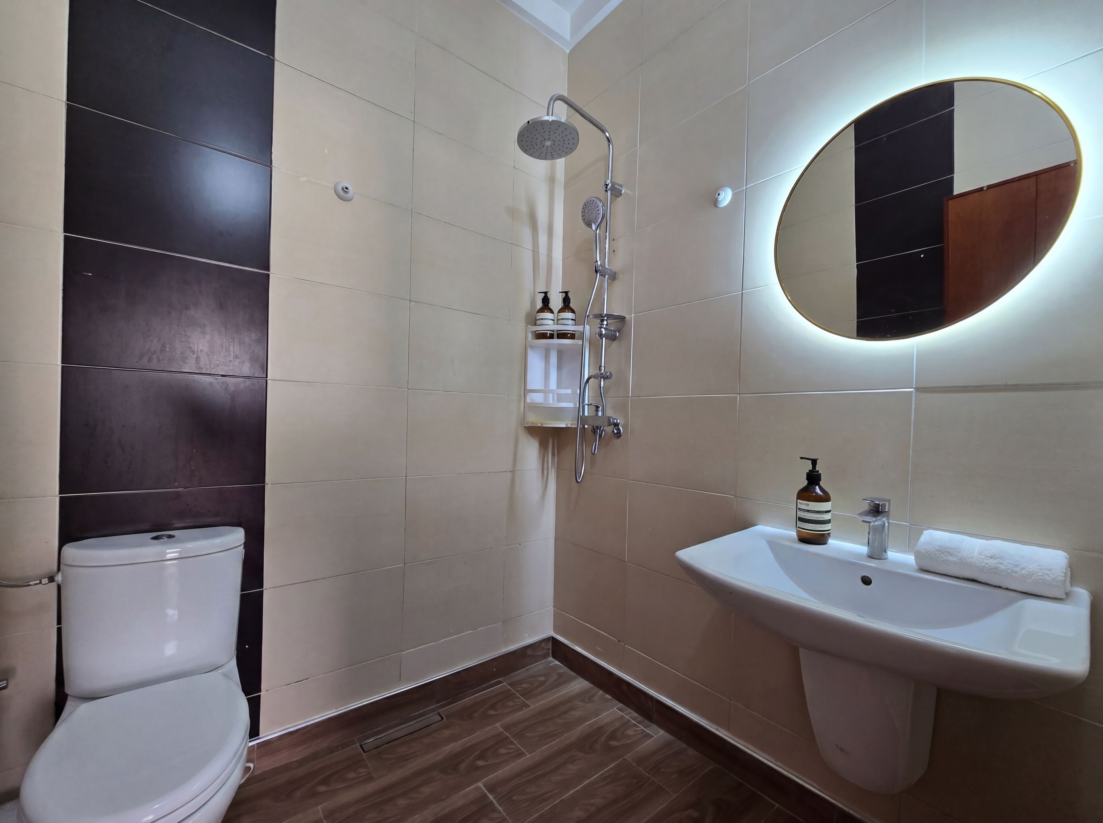 A bathroom with a toilet, a sink, a shower, and a mirror.