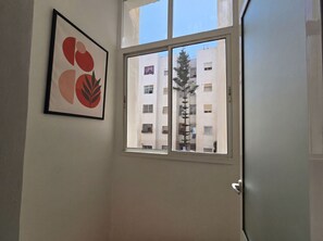A room with a window, a framed artwork on the wall, and a view of a building outside. - La Suite Salam , Family Oasis With Elevator (Agadir)