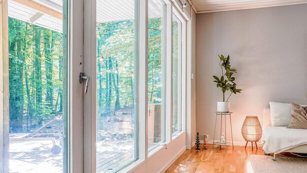 A room with large windows, a bed, a small table, and a potted plant. - 4 Person Holiday Home in Horby (Horby)