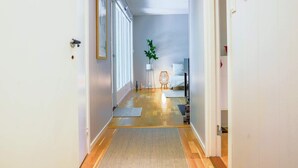 A hallway with a wooden floor, a rug, a plant, a bed, and a TV in a bedroom. - 4 Person Holiday Home in Horby (Horby)