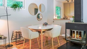 A modern kitchen with a central island, a dining area with a round table and chairs, and a fireplace. - 4 Person Holiday Home in Horby (Horby)