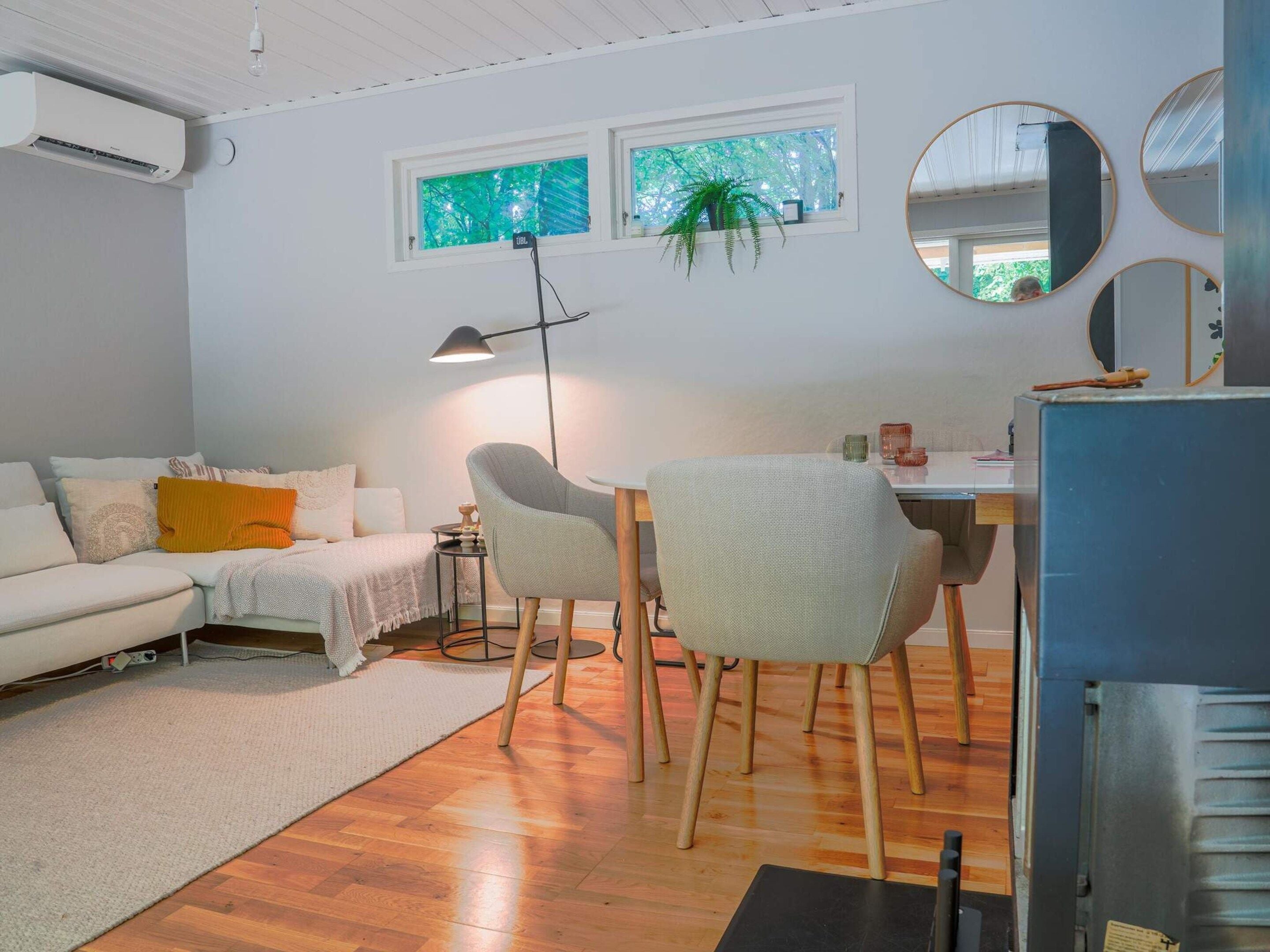 Un salon moderne comprenant un canapé, des fauteuils, une table à manger et une grande fenêtre donnant sur un beau paysage.