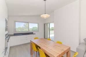 A modern kitchen with white cabinets, a wooden dining table, and yellow chairs. - Apartment 'Cala- Sea View Terrace' 150 Meters from Budoni Beach (Budoni)