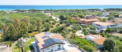 A residential area with houses, a clear sky, and a view of the sea.