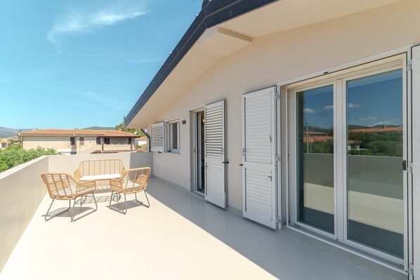 A balcony with a table and chairs, a sliding glass door, and a view of the surrounding area. - ‘Duna con Terrazza’ Apartment with Private Terrace, 3 Minutes from Budoni Beach (Budoni)