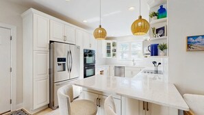 A modern kitchen with white cabinetry, stainless steel appliances, and a central island. - Gorgeous home with private pool - dog-friendly - only three blocks to the beach (Rehoboth Beach)