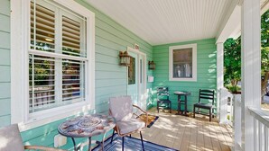 A porch with a table and chairs, a door with a number sign, and a window with shutters. - Gorgeous home with private pool - dog-friendly - only three blocks to the beach (Rehoboth Beach)