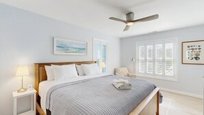 A bedroom with a bed, a nightstand, a lamp, a ceiling fan, and two windows with shutters. - Gorgeous home with private pool - dog-friendly - only three blocks to the beach (Rehoboth Beach)
