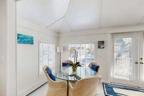 A dining area with a glass table, wicker chairs, and a potted plant. - Upgraded dog-friendly home 1.5 blocks to beach with lovely backyard & pool (Rehoboth Beach)