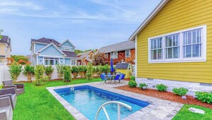 Ein wohnlicher Garten mit Swimmingpool, Terrassenmöbeln und einem gepflegten Rasen.
