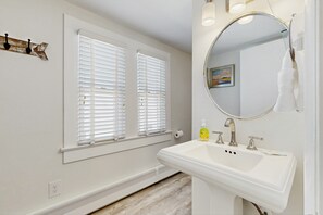 A bathroom with a white sink, a mirror, and a window with blinds. - Upgraded dog-friendly home 1.5 blocks to beach with lovely backyard & pool (Rehoboth Beach)