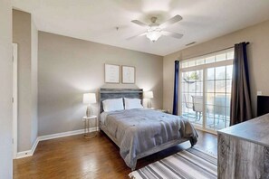 A bedroom with a bed, bedside lamps, a ceiling fan, and a large window with curtains. - Summerlyn Condo w/shared pool, patio, W/D and free WIFI (Lewes)