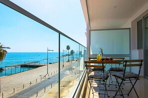 Varanda com vista para o mar, uma mesa com itens de café da manhã e uma cadeira.