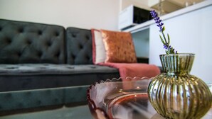 Een woonkamer met een bank, een glazen salontafel en een vaas met bloemen.