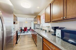A modern kitchen with stainless steel appliances, wooden cabinets, and a dining area with a red table and chairs. - Rehoboth Shores Estates spacious house w/ping-pong table, deck, WIFI (Rehoboth Beach)