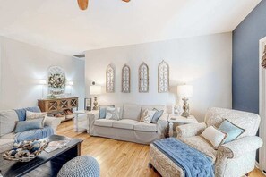 Ein Wohnzimmer mit einer Couch, einem Sessel, einem Couchtisch und Wanddekoration.