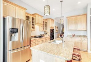 A modern kitchen with stainless steel appliances, wooden cabinets, granite countertops, and pendant lighting. - Sawgrass at White Oak Creek dog-friendly townhouse with a pool, tennis, & AC (Rehoboth Beach)