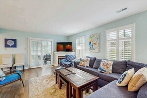 A living room with a sofa, coffee table, and TV. There is a fireplace, a chair, and a rug. - Keys of Marsh Harbor townhouse w/community pool & tennis court, deck, grill (Rehoboth Beach)