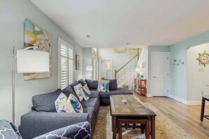 A living room with a sectional sofa, a coffee table, and a staircase leading to another level. - Keys of Marsh Harbor townhouse w/community pool & tennis court, deck, grill (Rehoboth Beach)