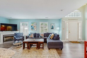 A living room with a fireplace, a sofa, a coffee table, and a TV. - Keys of Marsh Harbor townhouse w/community pool & tennis court, deck, grill (Rehoboth Beach)