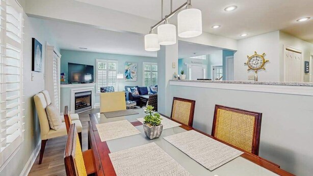 Uma sala de estar moderna com área de jantar, lareira e cozinha ao fundo.