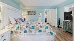 Quarto com cama, penteadeira, espelho e porta que dá para outro cômodo.