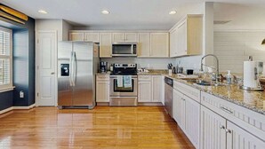 Eine moderne Küche mit Edelstahlgeräten, Holzschränken und einer Arbeitsplatte aus Granit.