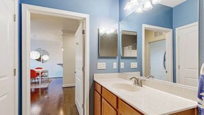 Un bagno con doppio lavandino, mobili contenitori in legno, uno specchio grande e un lampadario.
