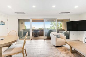 A modern living room with a dining table, sofa, and a TV. - Renovated Rehoboth Beach condo with ocean-view balcony - walk to beach (Rehoboth Beach)