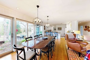 A spacious dining area with a large wooden table and chairs, a chandelier, and a view through large sliding glass doors. - Town of Rehoboth Beach dog-friendly home with fireplace & W/D - walk everywhere (Rehoboth Beach)