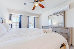 Ein Hotelzimmer mit Bett, Deckenventilator, Schminktisch, Spiegel und Fenster.