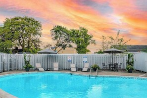 Ein Pool mit Liegestühlen und Sonnenschirmen, umgeben von einem Holzzaun.