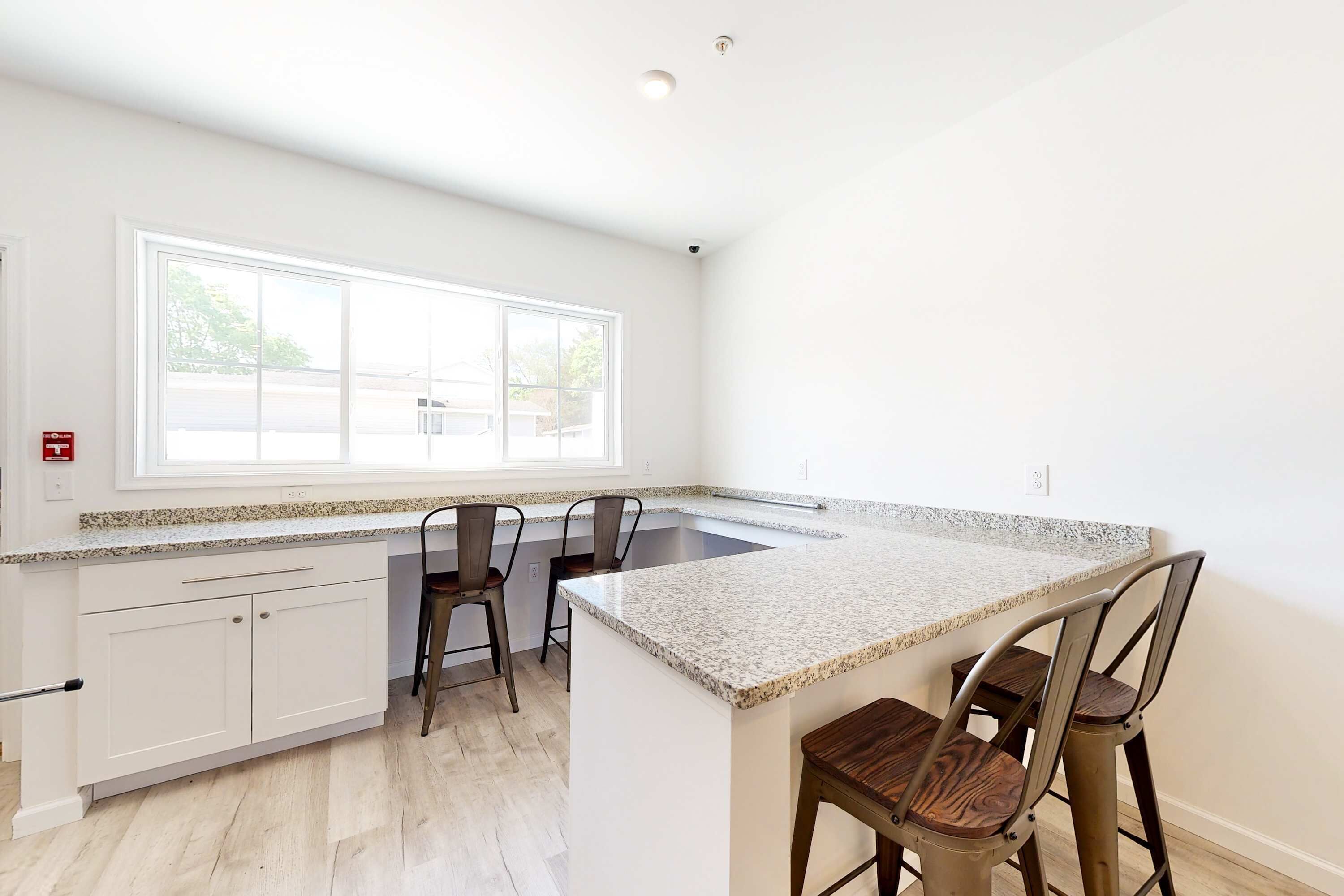 A kitchen with white cabinets, a granite countertop, and a window.