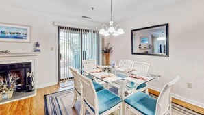 Un comedor con una mesa de vidrio, sillas blancas y una chimenea.