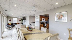 A dining area with a table, chairs, and a ceiling fan. There is a kitchen in the background with cabinets and a microwave. - Town of Rehoboth Beach apartment w/balcony, walk to beach (Rehoboth Beach)