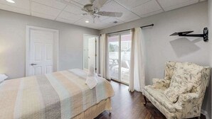 A bedroom with a bed, a chair, a ceiling fan, and a sliding glass door. - Town of Rehoboth Beach apartment w/balcony, walk to beach (Rehoboth Beach)