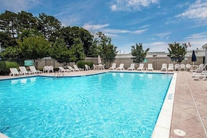 A swimming pool with lounge chairs and a fence. - Rehoboth Crossing Townhouse: Pool, AC and minutes from downtown Rehoboth Beach (Rehoboth Beach)