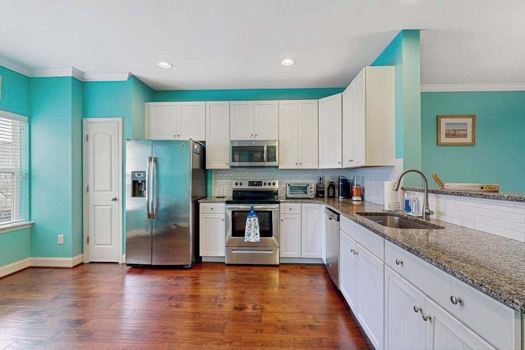 A kitchen with white cabinets, stainless steel appliances, and a granite countertop.
