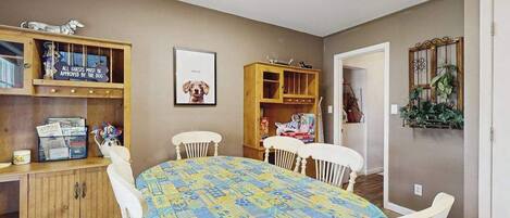 A dining area with a table, chairs, wooden cabinets, and a framed picture on the wall.