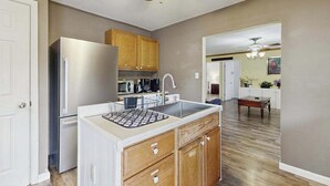 Una cucina con frigorifero, lavello, mobili in legno e una ventola a soffitto.