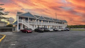 A motel with a two-story structure, a covered parking area, and a clear sky. - Rehoboth Beach House with amazing pool, clubhouse, & washer/dryer (Rehoboth Beach)
