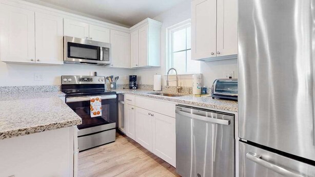 A modern kitchen with white cabinets, stainless steel appliances, and a granite countertop. - Rehoboth Beach House with amazing pool, clubhouse, & washer/dryer (Rehoboth Beach)