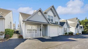 A residential house with a garage, a covered porch, and a driveway. - Eagles Landing townhome with pool and tennis access, patio & grill (Rehoboth Beach)